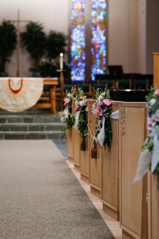 Church wedding ceremony with floral pew ties on the aisle seats created by District 2 Floral Studio.