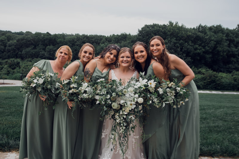Bride and bridesmaids in sage dresses all holding white and green July wedding bouquets by District 2 Floral Studio using locally-grown flowers.