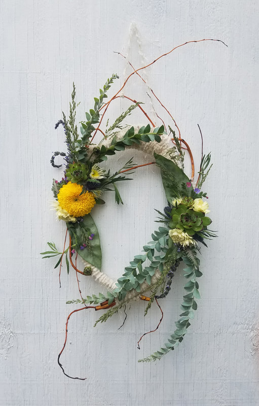 Wild curly willow, asymmetrical wreath with yellows and greens created by District 2 Floral Studio.