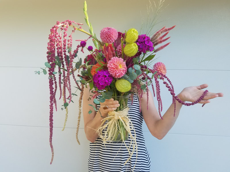 Holly holding a pink and yellow flower arrangement by District 2 Floral Studio created with locally grown flowers.