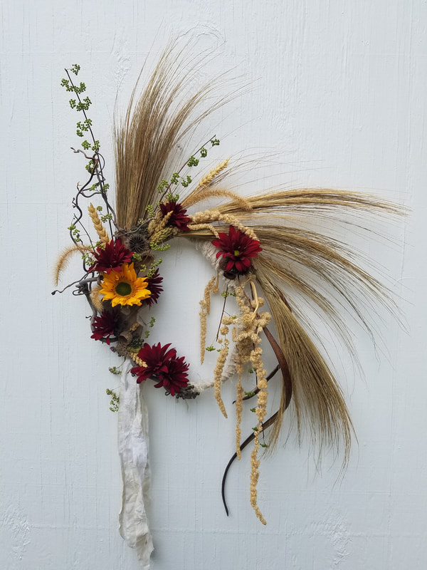 Asymmetrical wreath with grasses, sunflower and mums created by District 2 Floral Studio.