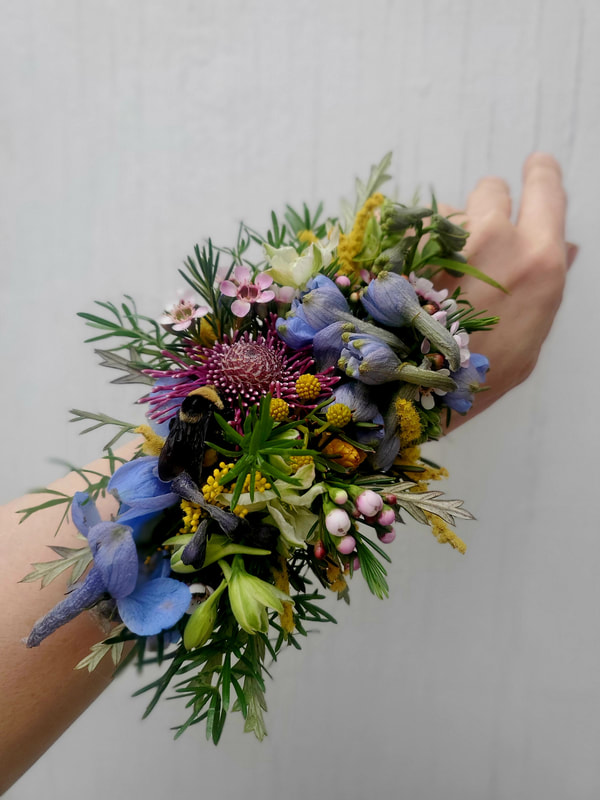 Hand wearing a wristlet corsage created with locally grown flowers created by District 2 Floral Studio.