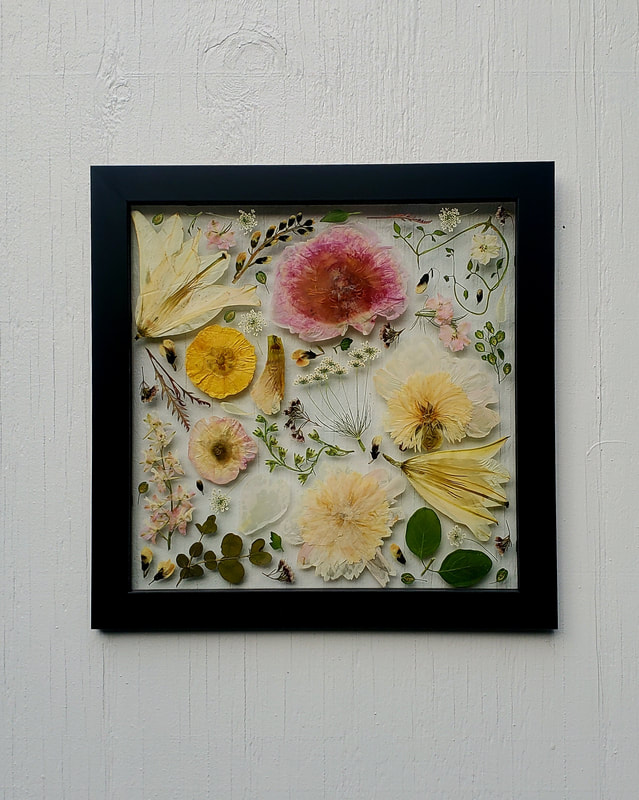 Pressed flower preservation piece by District 2 Floral Studio with peony and lilies in a custom black frame.