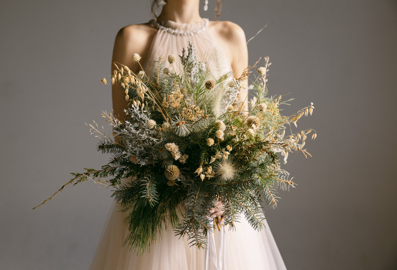 Bride holds a seasonal, winter wedding bridal bouquet by District 2 Floral Studio using locally-grown foliage and dried flowers.