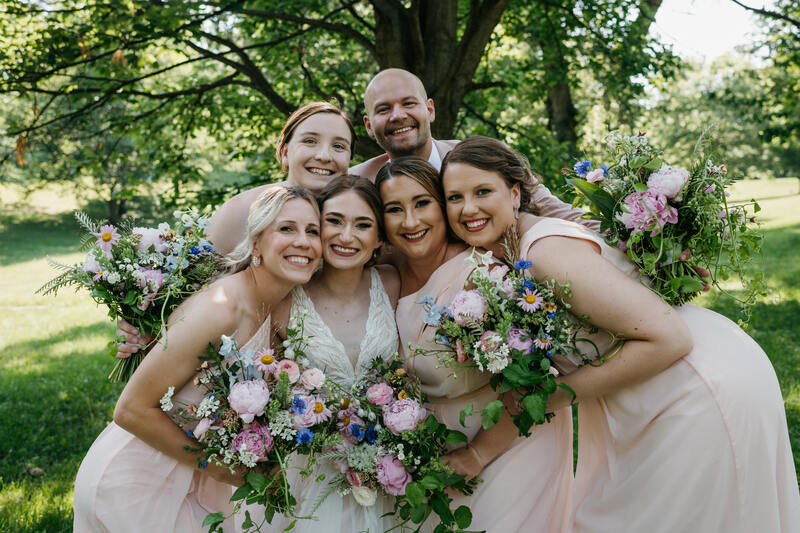 Bride and bridesmaids in  pastel pink dresses all holding pastel pink June wedding bouquets by District 2 Floral Studio using locally-grown flowers.