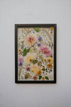 Pressed flower preservation by District 2 Floral Studio in a black frame.