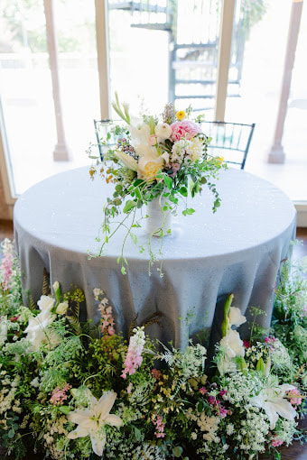 Wedding sweetheart table with the bridal bouquet in the center and flowers framing the lower edges of the round table. Created foam-free by District 2 Floral Studio.