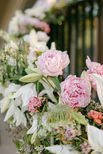 Up close of staircase railing covered in pink peonies and white lilies for a Spring wedding. Foam-free installation created by District 2 Floral Studio.