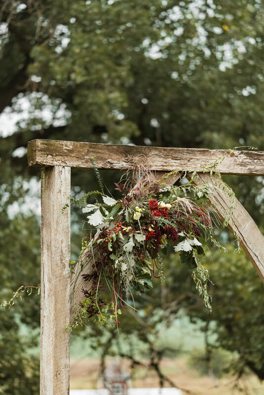Wooden arch has autumn Nebraska locally grown flowers adorning it created by District 2 Floral Studio.