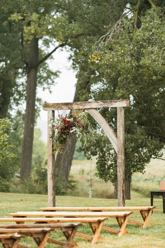 Wooden arch has autumn Nebraska locally grown flowers adorning it created by District 2 Floral Studio.