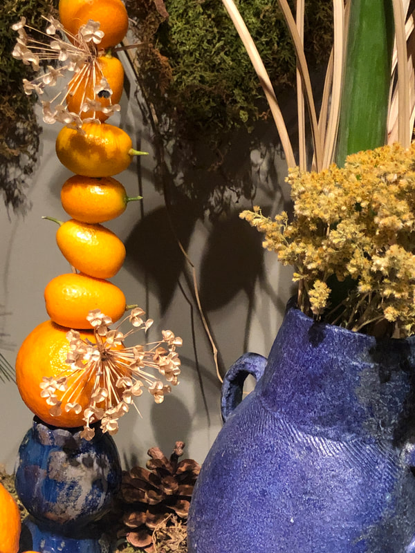 Up close view of seasonal winter floral installation by District 2 Floral Studio at a Cathedral with locally grown Nebraska evergreens, grasses, dried flowers, amaryllis and clementines and hand-built blue ceramic vases.