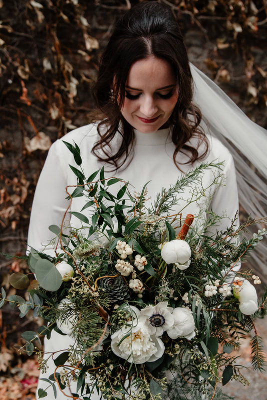 Bride holds a seasonal, winter November wedding bridal bouquet by District 2 Floral Studio using locally-grown foliage and white flowers.