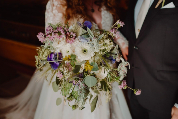 Bride holding a pastel pink, purple and white June wedding bridal bouquet by District 2 Floral Studio using local and American-grown flowers.