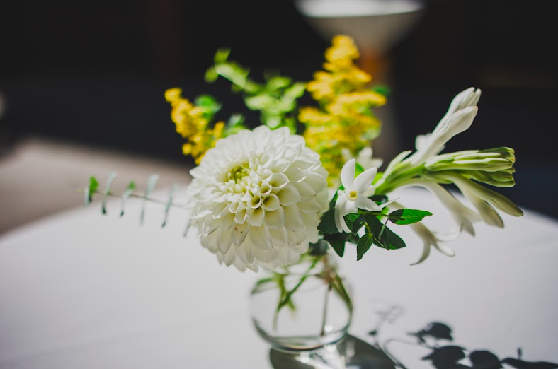 Yellow and white flower arrangement by District 2 Floral Studio created with locally grown flowers in a small glass vase.