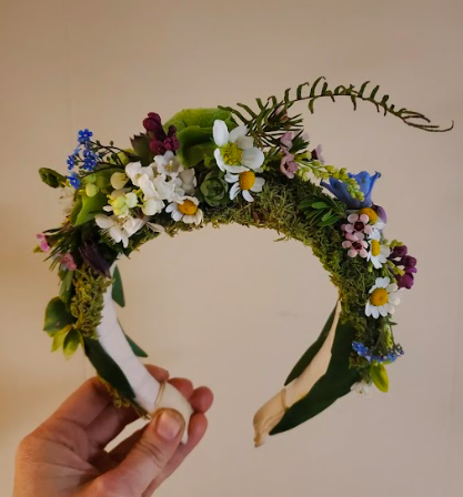 Hand holding a headband that is covered in moss and locally grown flowers created by District 2 Floral Studio.