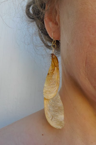 Up close of a human wearing a dangling earring created with samara helicopter seeds created by District 2 Floral Studio.
