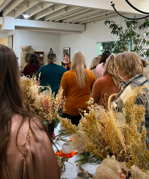 A group of adults watches attentively during a winter wreath design workshop with District 2 Floral Studio.