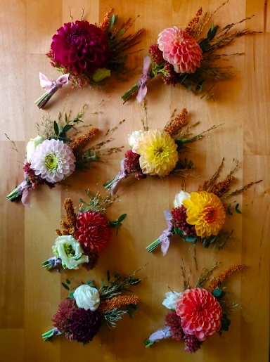 Flat lay of a series of wedding boutonnieres created by District 2 Floral Studio with Nebraska locally grown flowers, dahlias and lisianthus.