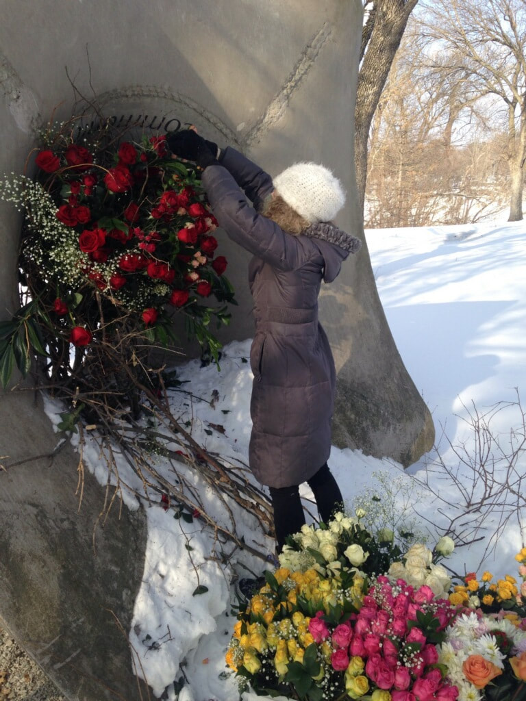 District 2 Floral Studio installs flowers outdoors in a park sculpture, Sounding Stones. The flowers are colorful against the white snow on the ground.